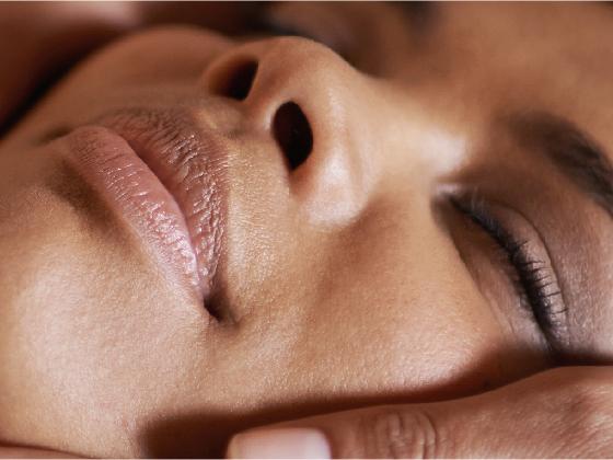Close-up of a person's face with eyes closed and a relaxed expression, suggesting they are enjoying a gentle facial massage or spa treatment.