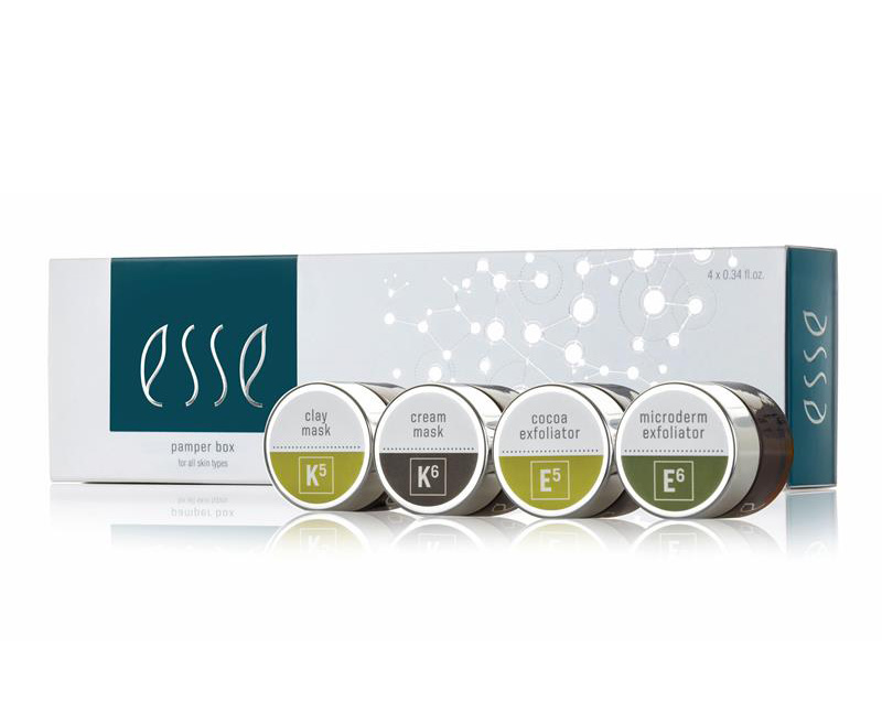 Four small jars labeled clay mask, cream mask, cocoa exfoliator, and microderm exfoliator are displayed in front of a rectangular Esse Pamper Box package for skin care.