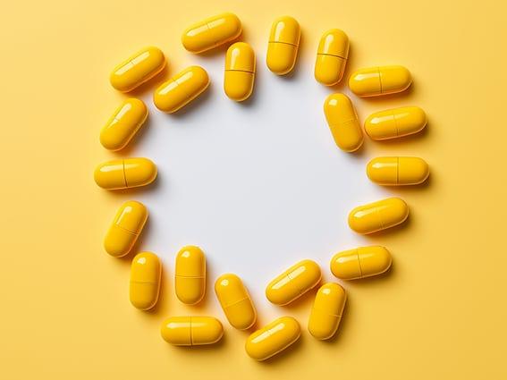 Yellow capsules arranged in a circle on a yellow background, leaving a white empty space in the center.